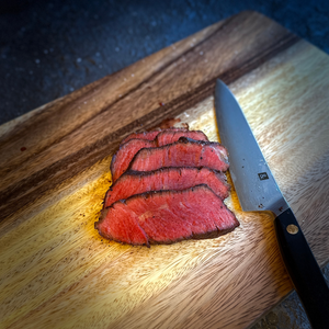 Sliced beef on a wooden cutting board with a knife