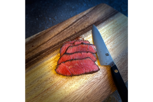 Sliced beef on a wooden cutting board with a knife