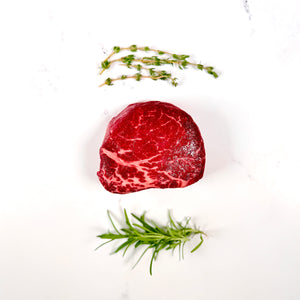 Raw steak with thyme sprigs on a white background