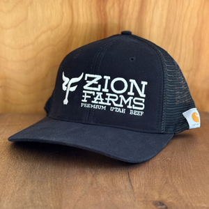 Navy blue cap with 'Zion Farms' logo on a wooden surface