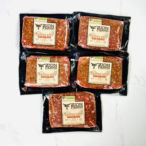 Five packages of Zion Farms ground beef on a white background