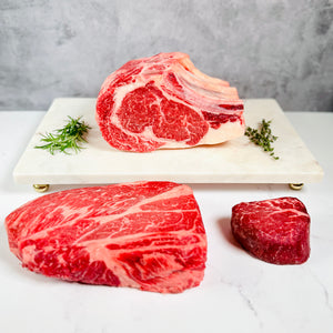 Three pieces of raw beef on a white marble slab with a gray background. Zion Farms Holiday Box