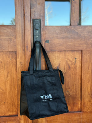 Black insulate tote with a Zion Farms logo attached to a wooden door