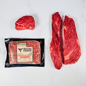 Packaged ground beef from Zion Farms with two raw steaks on a white background. Mountaineer Box