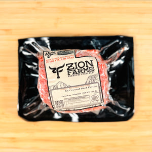 Packaged ground beef patties from Zion Farms on a wooden surface